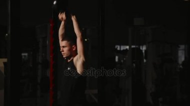 Kaslı adam spor salonunda ağırlık egzersizleri yapıyor. Kettlebell parçalarının.