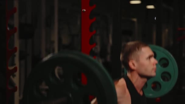 Молодий м'язистий чоловік у спортзалі виконує присідання . — стокове відео