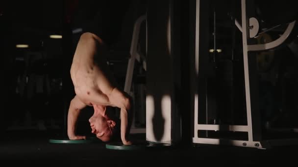 Musculoso hombre de pie en las manos en el gimnasio por la pared realiza push-UPS . — Vídeos de Stock