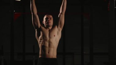 Spor haddelenmiş adam çubuğunda bacak yükseltir ve trenler karın kasları. Bir t-shirt.