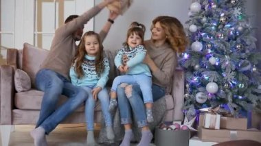 Mutlu aile Noel, anne, baba ve iki küçük kız evde Noel ağacı yakınındaki kanepede oturan hediyeler açmak için.