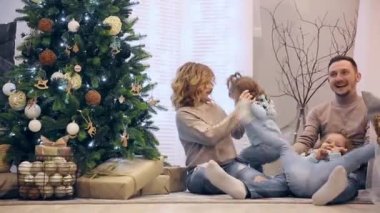 Kazak anne baba ve Noel ağacın altında oturup, gülen ve birbirlerine çikolata satın iki kızı mutlu aile.