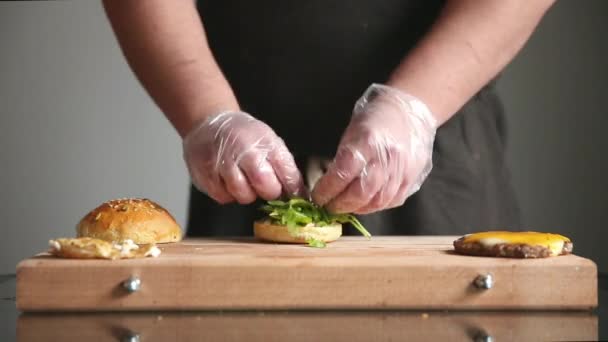 Um chef profissional prepara um cheeseburger com uma costeleta grande e uma salada. Desfasamentos temporais . — Vídeo de Stock