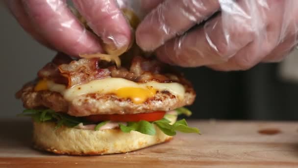 O processo de cozinhar hambúrguer grande é um chef profissional, close-up. Coloca rissóis com queijo em um pão — Vídeo de Stock