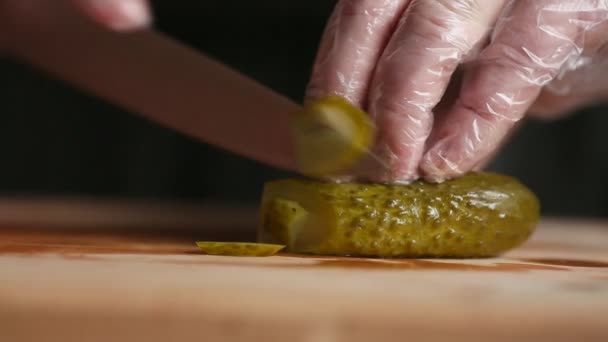 Een professionele chef-kok snijdt een komkommer in handschoenen. — Stockvideo