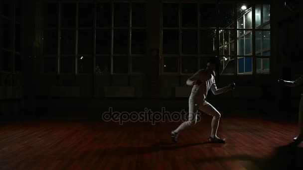 Jeune homme et jeune femme vêtus de costumes pour la pratique de l'escrime dans la salle de sport. De retour sur le fond, il neige . — Video