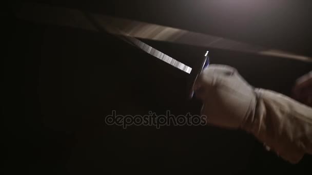 Gros plan d'une rapière pour l'escrime dans la main effectue des mouvements offensifs. Attaque à l'épée masculine. Vue latérale .