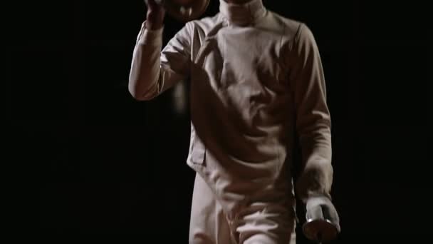 A man dressed for fencing wears a mask and is preparing a rapier. Close-up. Camera movement from the bottom up — Stock Video