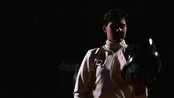 Close-up of a girl dressed for fencing wear a helmet and becomes a rack to match. — Stock Video