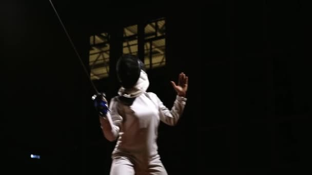トレーニングで女の子剣士は攻撃する突進を満たしています。暗い背景. — ストック動画