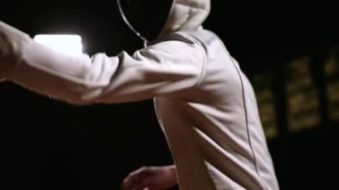 Bir adam koyu arka plan üzerinde bir rakip ile kıskaç eskrim için kask içinde closeup.