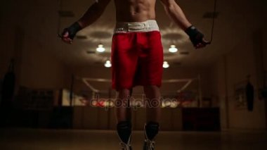Bir pompalı-up adam boks Ayakkabı ve spor salonu zemin bir boks halka karşı şortla. Dikey kamera hareketi
