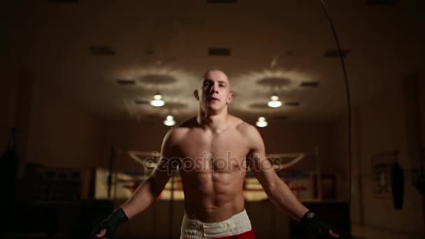 En pumpas upp mannen i boxning skor och shorts i gymmet mot bakgrund av en boxningsring. Närbild — Stockvideo