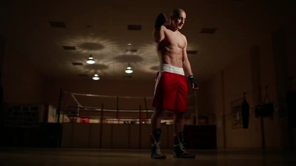 Ein professioneller Boxer im Hintergrund des Rings, der vor dem Sparring die Hände beugt. — Stockvideo