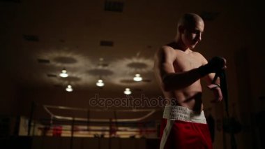 Bir pompalı-up adam boks Çizmeli ve spor salonu Boks ringi çerçevede şortla bandaj ellerinde elbiseler.