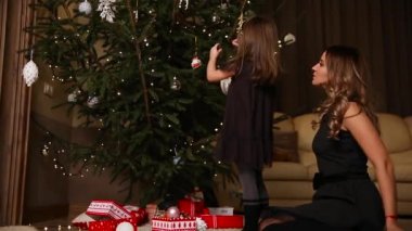 Anne ve kızı renkli topları ile Noel ağacı süslemeleri.