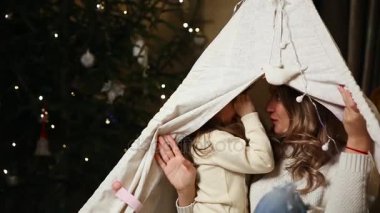 Anne ve kızı kendi evin içinde bir çadırda otururken Noel için onların arzularına birbirlerinin kulaklara söyle. Kızı güler.