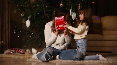 Anne ile etkileyici duymak için bir hediye kutusu sallıyor. Küçük kızı bir hediye açar