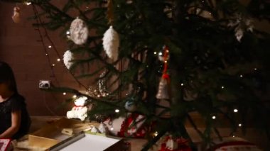 Annem ve onun kızı oturup evde dekore edilmiş bir Noel ağacı altında hediyeler düşünün