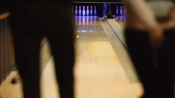 V herní klub pro bowling hráč hodí bowlingovou kouli, která srazí kuželky. Zaměřte se na kolíky. Rozšířenou hru a hráč vykrojí vítězný úder pro tým. Zastřelil všechny kolíky. — Stock video
