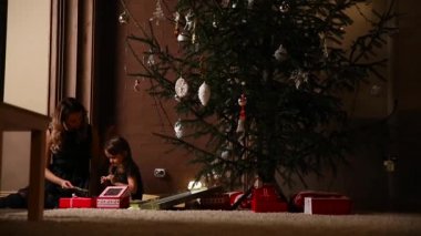 Noel arifesinde Noel ağacının altında oturan, annem Hediyelik kurdeleler bağlı kızı hediye ve çözdükten kız verdi. Kamera hareketi