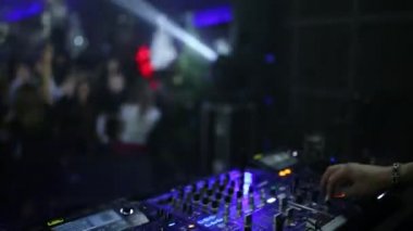 Bir parti bir gece kulübünde çalışan bir profesyonel Dj kişilik bir kalabalık rüzgarlar ve müzik karışımları. DJ uzaktan kumanda yakın çekim. insanlar içinde belgili tanımlık geçmiş ile dans pisti.