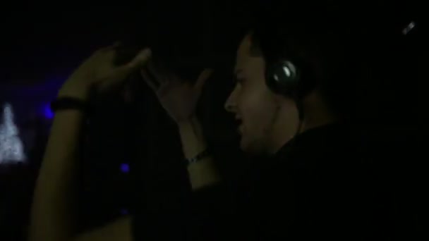 DJ fait danser la foule les gens bougent les mains dans les écouteurs. fête dans la boîte de nuit . — Video