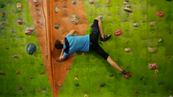 Professional rock climber climbs the sheer wall without equipment and breaks down. The climbing wall. The climbing wall in the room. — Stock Video