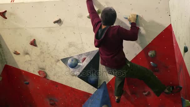 A rock climber climbs a steep wall and breaks down after a failed attempt to climb to the top. A climbing wall indoors. — Stock Video