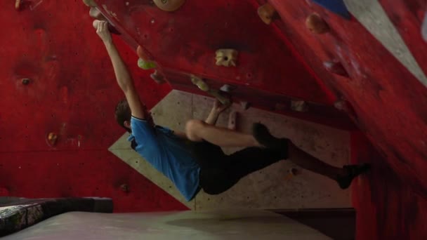 O alpinista está treinando para escalar uma montanha com um grande ângulo. Um atleta profissional. Totalmente pendurado acima do solo. Parede horizontal — Vídeo de Stock