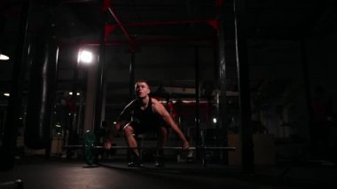 bir erkekte siyah spor salonunda bir egzersiz ağır dekolmanı için - bir pislik gerçekleştirir..