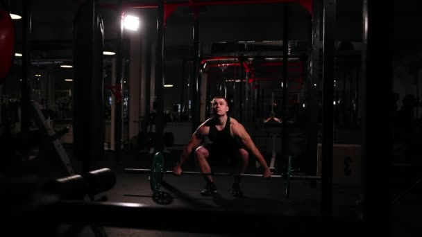 Un athlète sportif dans la salle de gym lève la barre avec un poids au-dessus de sa tête de la position assise . — Video