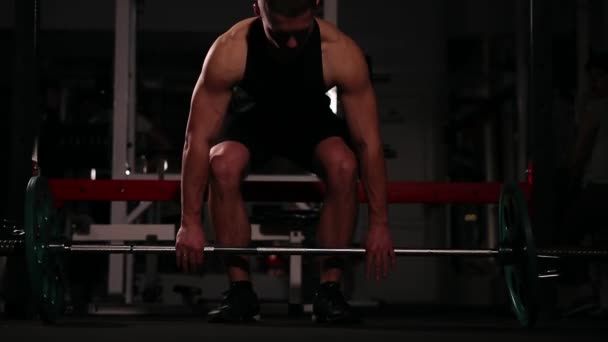 De atleet in zwarte kleding duwt de bar met een gewicht boven zijn hoofd in een dynamische tempo. — Stockvideo