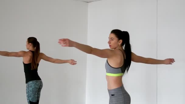 Dos chicas sobre fondo blanco en el gimnasio dan una lección de pilates . — Vídeos de Stock