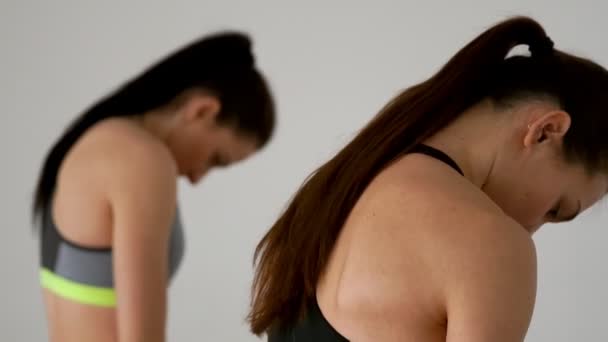 Close-up de 2 meninas fazendo exercícios de Pilates. Vista traseira. Inclinar lentamente e esticar os músculos pélvicos. A câmera se move de cima para baixo . — Vídeo de Stock