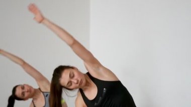 Güzel kızlar yamaçlarında yan dizlerinin üzerinde egzersizleri Pilates için gerçekleştirin. Pratik yoga yaparken elleri yumuşak hareketleri. Yakın çekim kamera bir kızdan diğerine taşır. Kız adlı arıyor