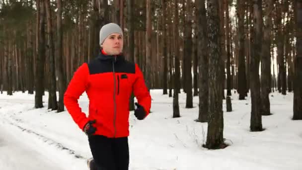 Молодий спортсмен їде в спорт у лісі на бігу взимку — стокове відео