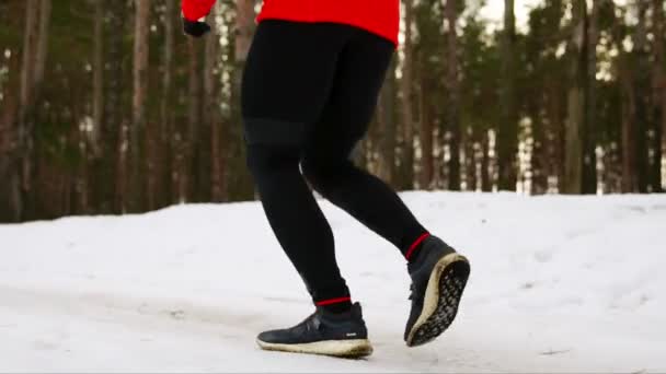 Detail nohy běží v zimě na sněhu v teniskách po lese. Zpomalený pohyb. 120 snímků za sekundu — Stock video