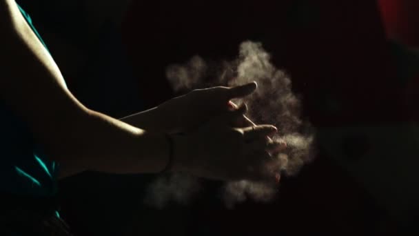 Close-up on a black background with a hand of a professional balder. Apply chalk on your hands against slipping. Cotton and dust scattered in different directions. — Stock Video