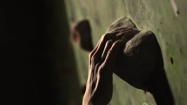 Primer plano de un escalador sube a una pared de piedra en el interior. La Escultura. La mano se fija en el acabado. El ejercicio se ha completado . — Vídeo de stock