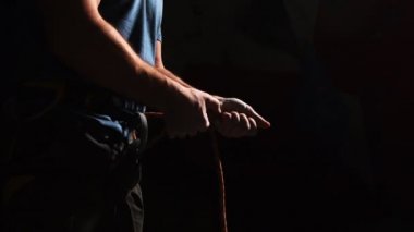 Siyah bir arka plan üzerine bir dağa tırmanmak için bir dağcı ipi bağları bir atlet el vinç. Ağır çekim. dağcılar sigorta hazırlanması