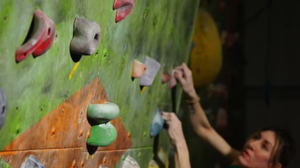 A female boulder trains to overcome obstacles on the wall for climbers. Professional rescuer. Climbing Wall. competitions without insurance. — Stock Video