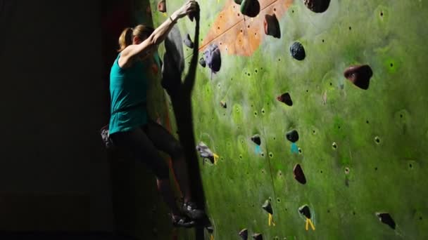 Крупный план руки женщины-альпинистки, которая лезет на стену для скалолазания вдоль стены, спотыкаясь на соревнованиях без страховки. Медленное движение — стоковое видео