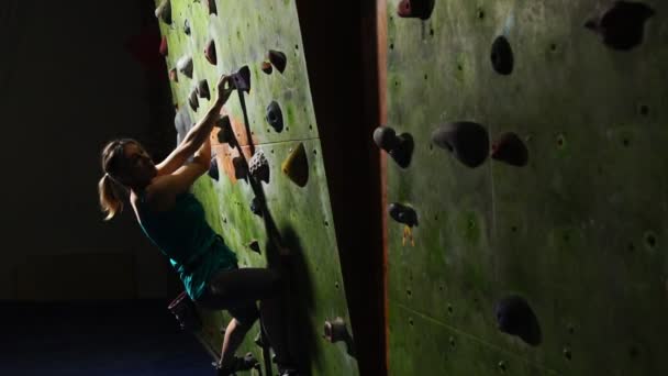 Крупный план руки женщины-альпинистки, которая лезет на стену для скалолазания вдоль стены, спотыкаясь на соревнованиях без страховки. Медленное движение. Альпинист — стоковое видео