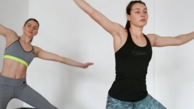 Kızlar yamaçları ve farklı yönlere ellerini tutarak sol diz çökmüş gerçekleştirin. Genç kız yoga nişanlandık. Pürüzsüz hareketleri Pilates. Kamera yörüngede hareket eder.