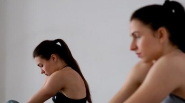 Güzel kızlar bir kelebek duruş otururken duruş için bir egzersiz yapmak. Pilates. Yoga. Odağı bir kişi diğerine değişir. Yakın çekim. Spor kız portresi. Bir grup insan gir