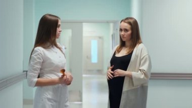 Kadın doktor ve hamile bir genç kadın organ nakli Merkezi koridorda durmak ve doktor durumu ve tabii ki gebelik hakkında sorular sorar. Midesini onunla dokunduğu