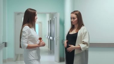 Perinatal Merkezi koridorda duran bir hamile kadın kadın doktor ile iletişim kurar..