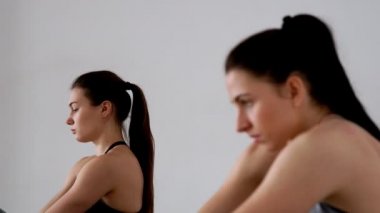 Güzel kızlar bir kelebek duruş otururken duruş için bir egzersiz yapmak. Pilates. Yoga. Odağı bir kişi diğerine değişir. Yakın çekim. Spor kız portresi.