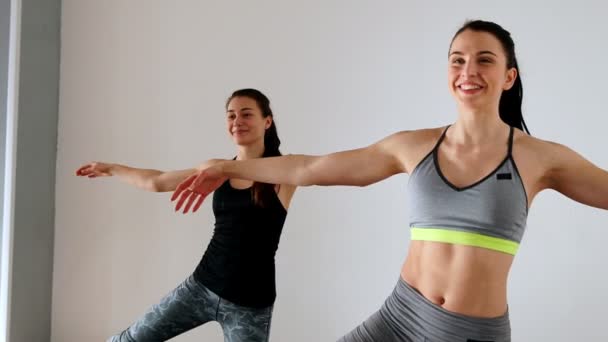 Две красивые атлетические девушки на коленях разводят ноги и руки симметрично в боковых упражнениях пилатеса . — стоковое видео